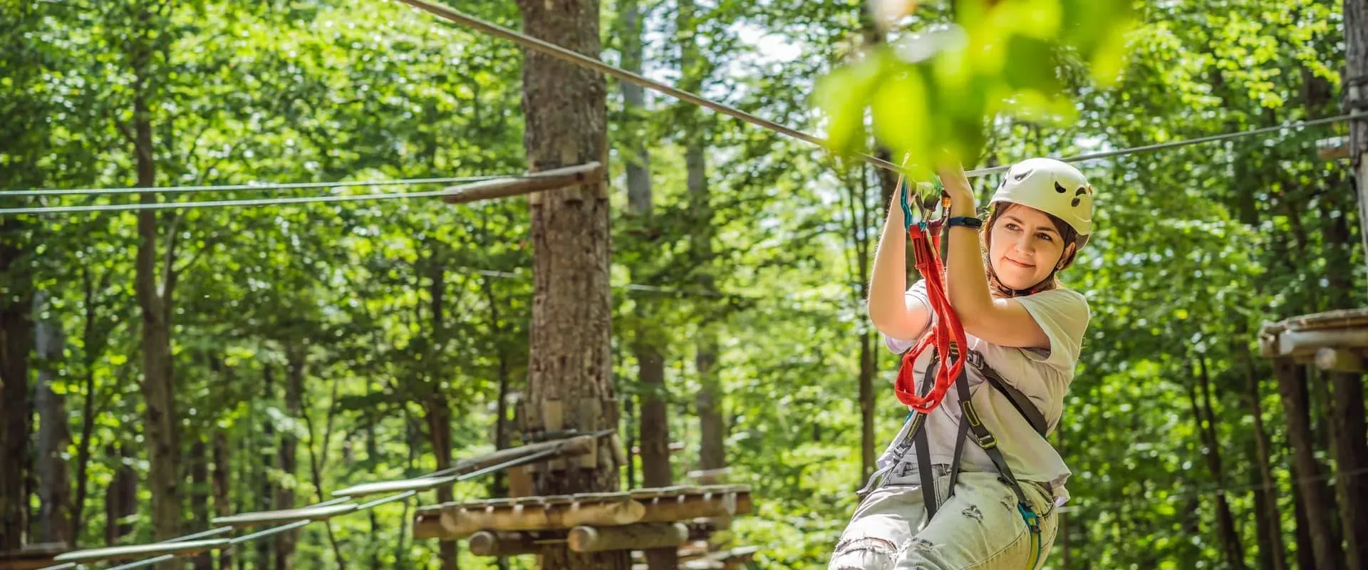 Meisje met helm en harnas op zipline in groen klimbos