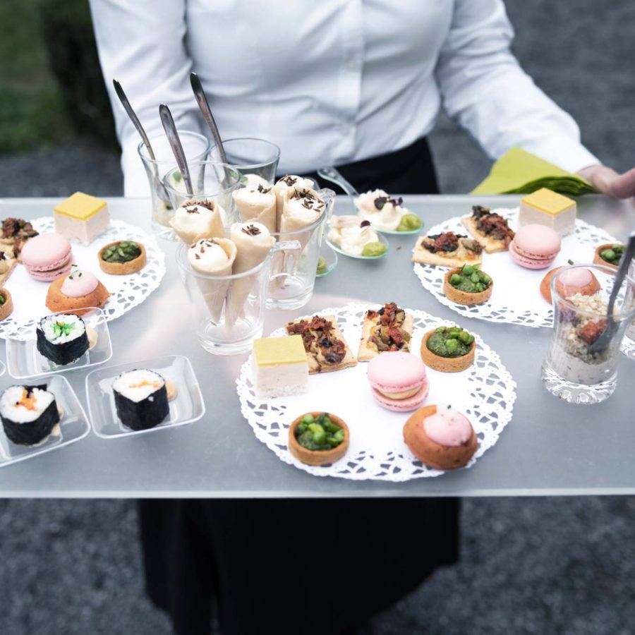 Ober draagt plateau met hapjes, macarons en sushi
