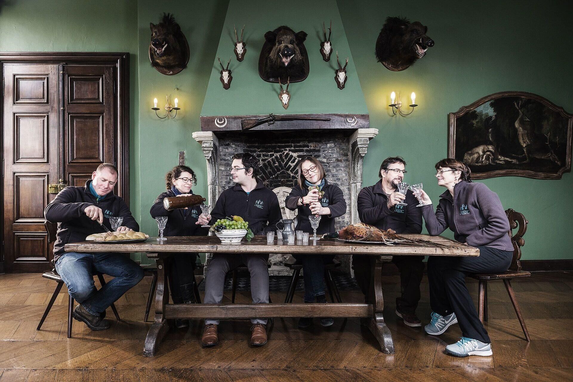 Team proeft bier aan tafel in kasteelzaal met jachttrofeeën