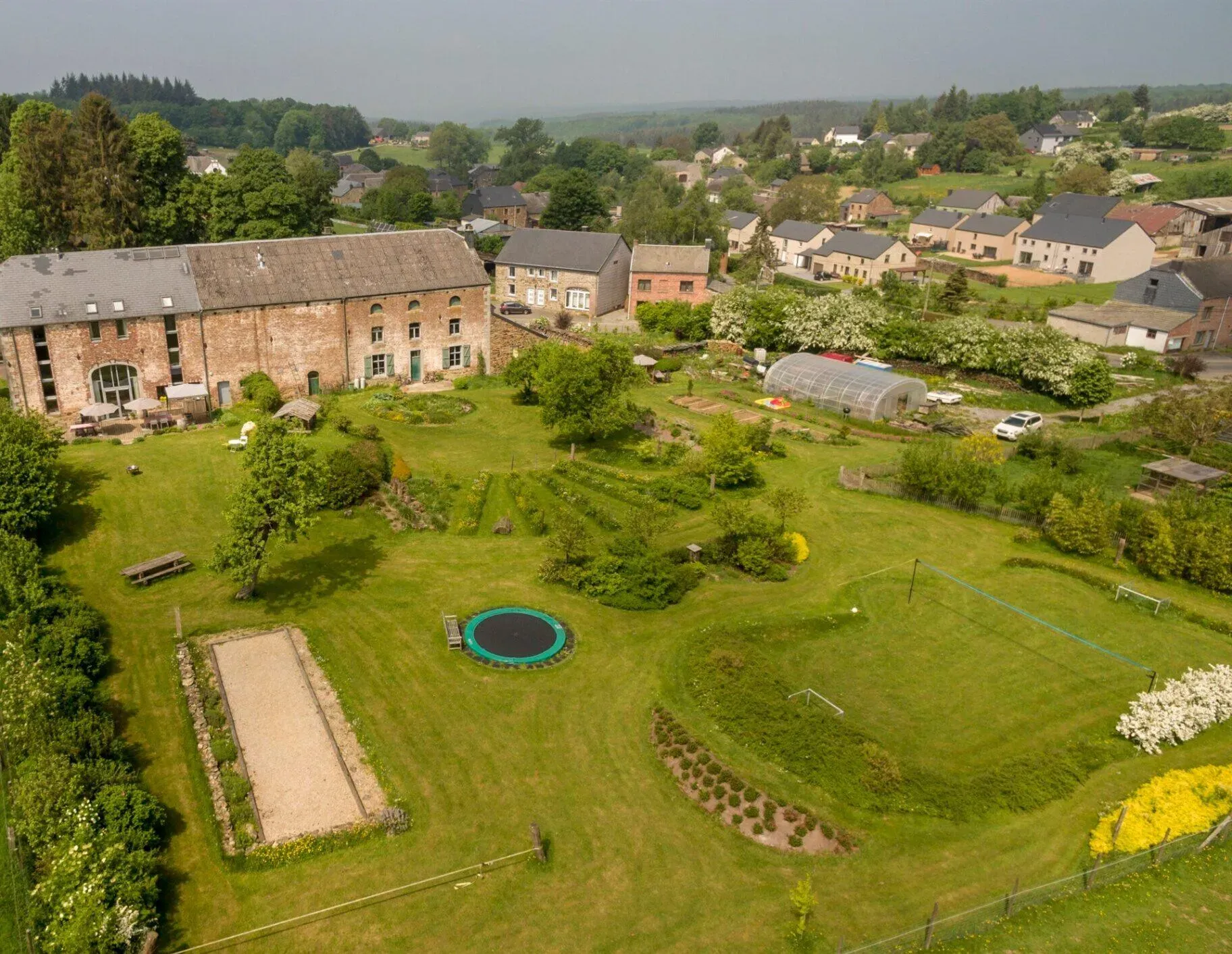 Luchtfoto van de 2 hectare grote tuin met speeltoestellen en voetbalveld