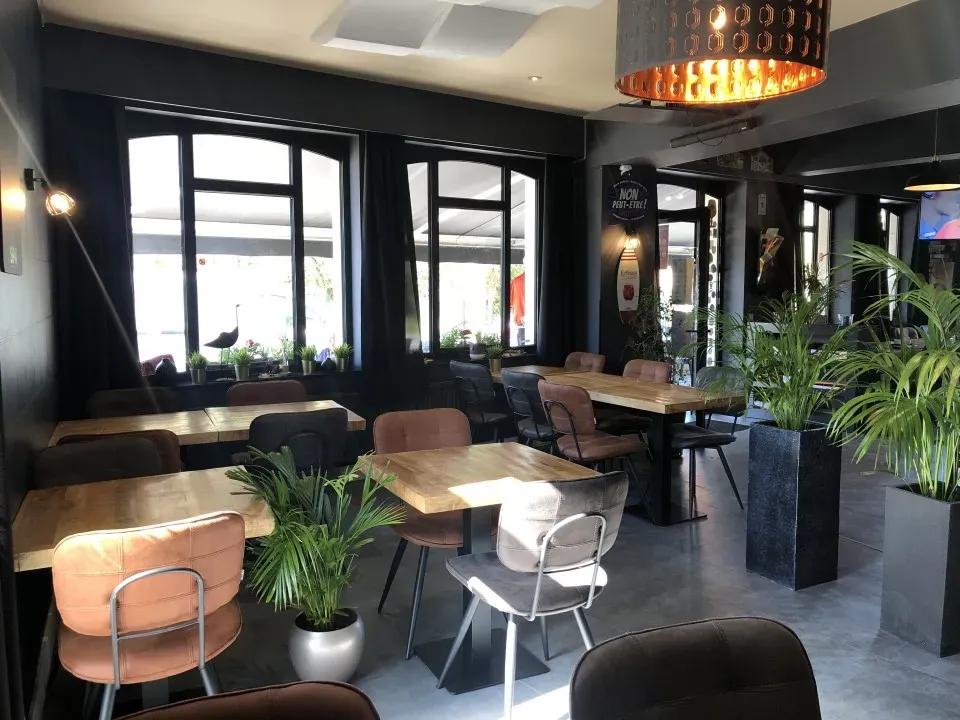 Stijlvol donker interieur van Le Belvédère met houten tafels en planten