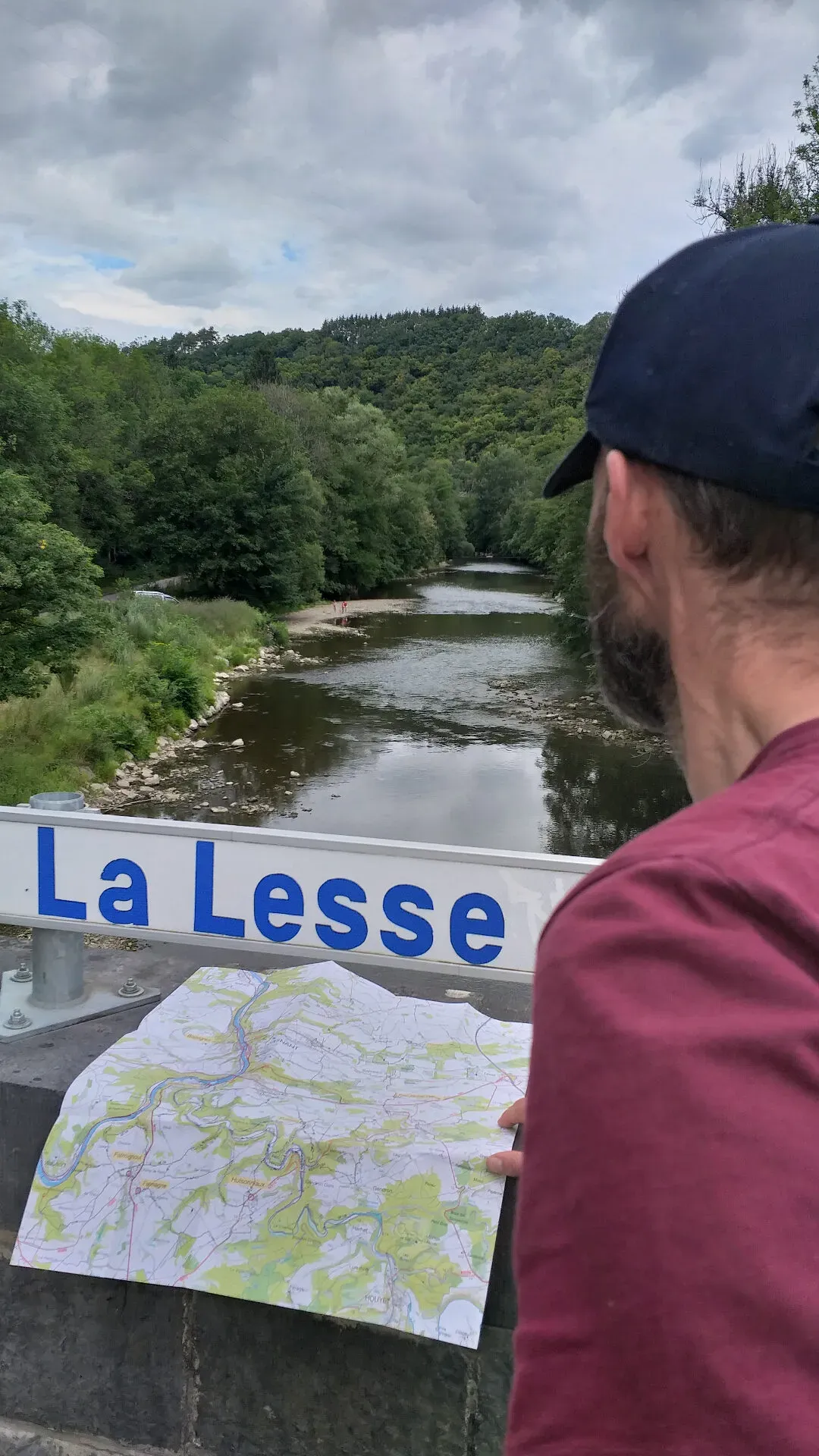 Wandelaar bekijkt kaart bij bord La Lesse met uitzicht op de rivier