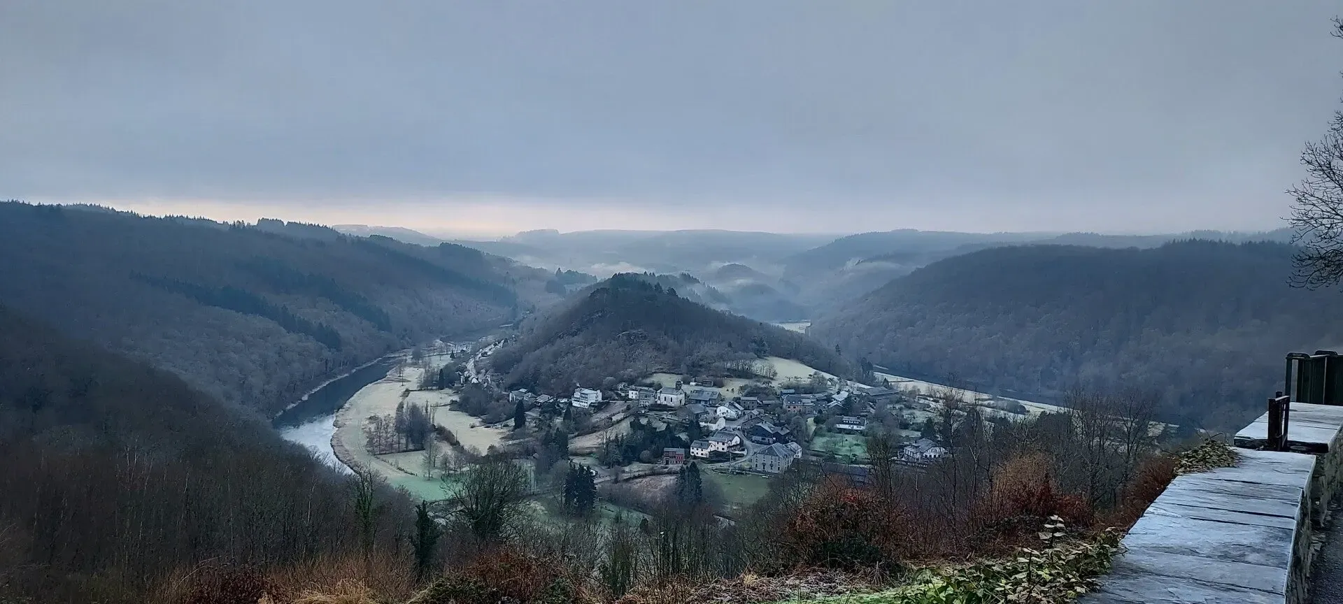Panoramisch uitzicht op Semois-meander en dorpje in mistig winterlandschap