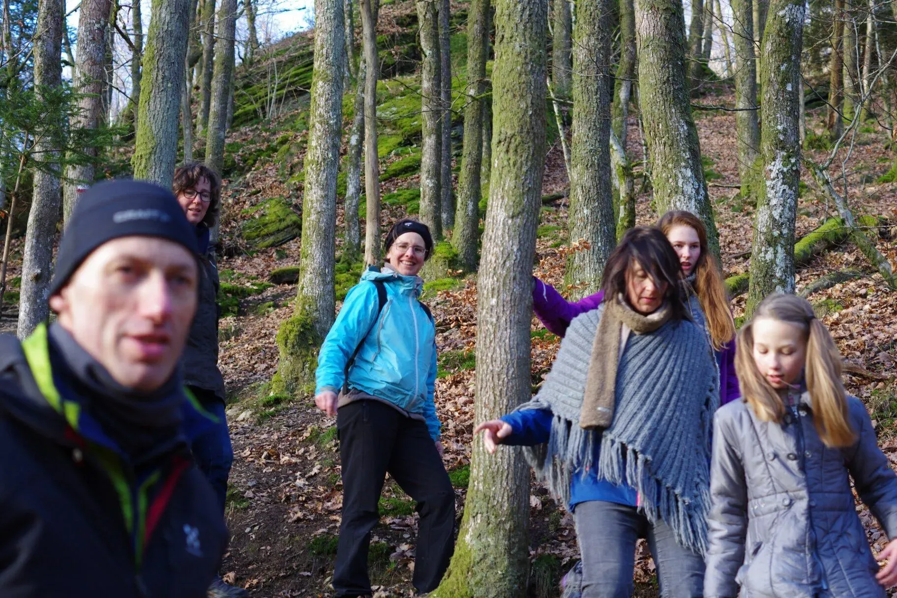 Groep wandelaars poseert lachend tussen boomstammen op steile helling