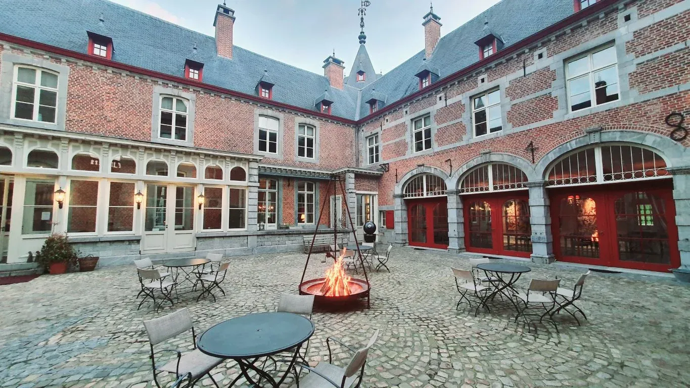 Het binnenplein van Château de Jemeppe met vuurkorf en rode deuren (foto chateaujemeppe.be)