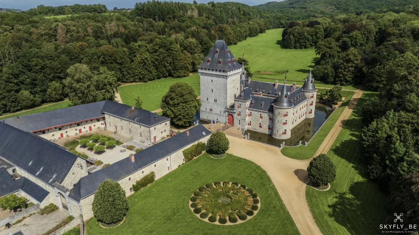 Luchtfoto van de hoeve en het binnenplein van Château de Jemeppe, met de donjon en de slotgracht erachter (foto Skyfly.be via chateaujemeppe.be)